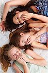 Teenage girls lying on bed and giggling