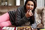 Teenage girl eating chocolates on sofa