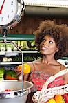 Femme afro-américaine pesant poivrons à échelle au supermarché