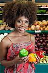 African American woman holding bell peppers at supermarket