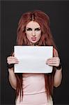 Portrait of arrogant young funky woman with blank placard standing against black background