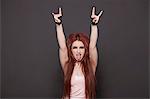 Portrait of funky young woman sticking out tongue and making rebellious gestures over black background