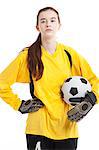 Portrait of young female soccer player holding ball with hand on hip against white background