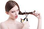 Beautiful young woman with scissors cutting her hair over white background