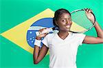Portrait de jeune femme avec une raquette de tennis contre drapeau brésilien