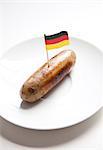 Fried sausage in plate with German flag decoration against white background