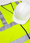 Safety vest and hard hat against white background