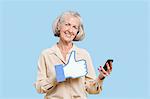 Portrait de femme senior avec téléphone portable maintenant faux comme bouton sur fond bleu