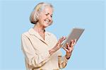 Happy senior woman using tablet PC against blue background