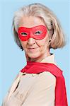 Portrait of senior woman wearing superhero costume against blue background