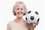 Portrait of senior woman holding soccer ball against white background