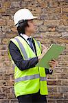 Young male supervisor writing notes at construction site