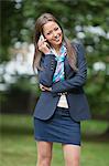 Portrait of happy businesswoman using cell phone at park