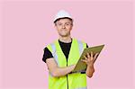 Portrait of a male construction worker with clipboard over pink background