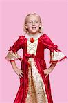 Portrait of a happy young girl dressed in princess costume over pink background