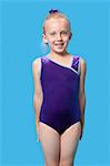 Portrait of a happy female gymnast standing over blue background