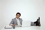 Businessman sitting with feet on desk, looking at newspaper