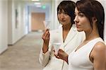 Businesswomen taking break and drink from disposable cups in hallway