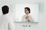 Man adjusting shirt collar in mirror