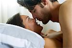Jeune couple romancing dans son lit, vue latérale