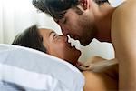 Young couple romancing in bed, side view