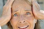 Senior woman holding head, distressed expression on face