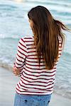 Young woman standing at beach, rear view