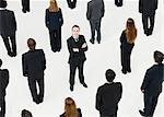 Businessman with arms crossed standing in midst of anonymously dressed business professionals