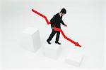 Businessman descending steps holding arrow pointed downward