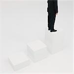 Businessman standing on highest step, cropped