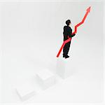 Businessman standing at top of steps holding arrow pointed upward