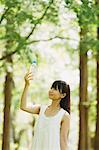 Femme asiatique dans une robe blanche, tenant une bouteille d'eau dans les bois