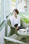 Japanese woman in a white shirt sitting on a wicker chair