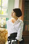 Japanese woman in a white shirt sitting and looking away