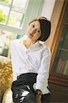 Japanese woman in a white shirt sitting and looking at camera