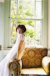 Japanese woman in a white dress leaning against a sofa