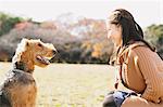 Japanese woman with long hair and a dog in a park looking at each other