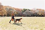 Japanese woman with long hair walking her dog in a park