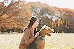Japanese woman with long hair and a dog in a park looking away