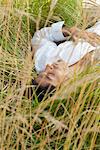 Man lying in tall grass with eyes closed