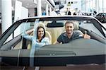 Young couple in a cabriolet in the showroom