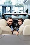 Young couple in a cabriolet in the showroom