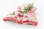 Raw spare ribs with rosemary on white background