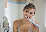 Young woman brushing teeth with electric toothbrush