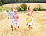 Family Running Together Through Summer Harvested Field