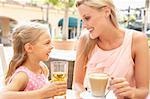 Mother And Daughter Enjoying Cup Of Coffee And Juice In Caf? Together