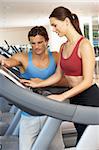 Woman Working With Personal Trainer On Running Machine In Gym