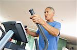 Senior Man On Cross Trainer In Gym