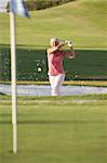 Senior Female Golfer Playing Bunker Shot On Golf Course