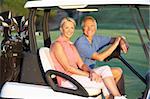 Senior Couple Riding In Golf Buggy On Golf Course